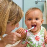 Мама учит малыша чистить зубы